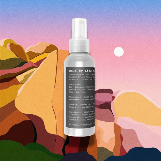 Spray bottle labeled 'crux by Life' against a colorful abstract landscape background